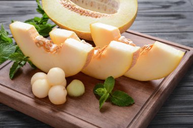Olgun kavun topları ve ahşap tahta üzerinde nane ile dilimlenmiş
