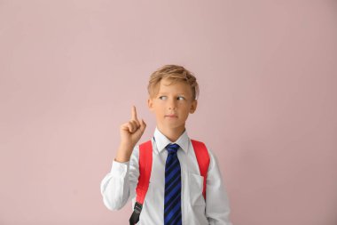 Renk arka plan üzerinde yükseltilmiş işaret parmağı ile şirin küçük öğrenci