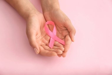 Pembe kurdele renk arka plan üzerinde tutan kadın. Meme kanseri kavramı