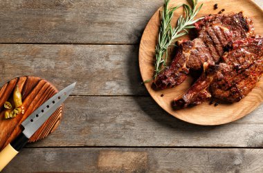 Ahşap masa üzerinde lezzetli ızgara biftek ile plaka