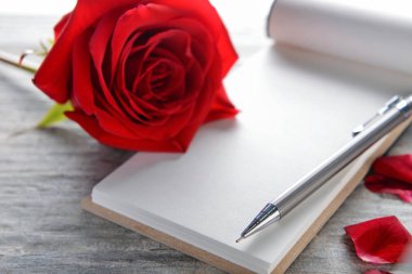 Güzel kırmızı gül ve ahşap arka plan, closeup üstünde defter