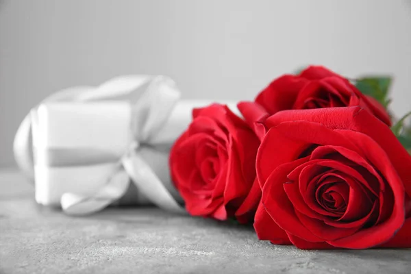 Schöne Rote Rosen Und Geschenk Auf Grauem Tisch — Stockfoto