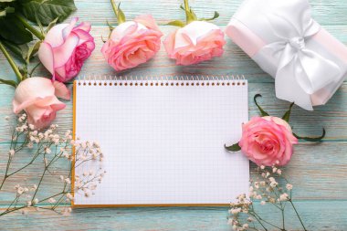 Güzel gül, hediye kutusu ve ahşap masa üstünde defter