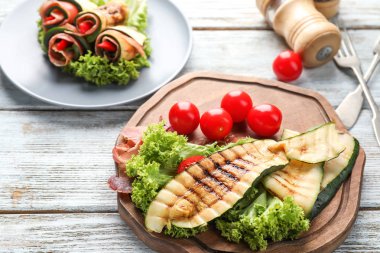 Lezzetli kızarmış kabak, domates ve hafif ahşap masa üzerinde rulo ile kurulu