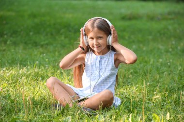 Sevimli küçük kız yaz gününde Park müzik dinlemek