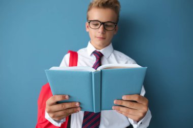 Renk arka plan üzerinde kitap okuma sırt çantası ile genç çocuk