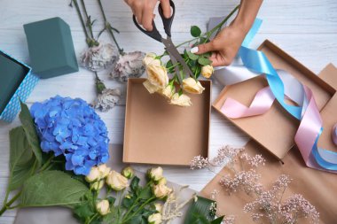 Kadın çiçekçi masaya güzel çiçek kutusuyla hazırlanıyor