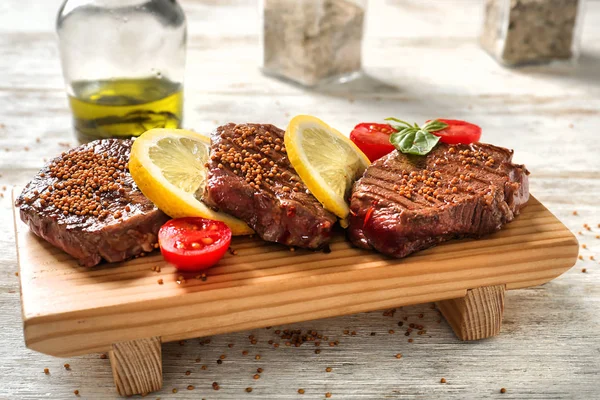 Brett Mit Leckeren Steaks Vom Grill Auf Hellem Holztisch — Stockfoto