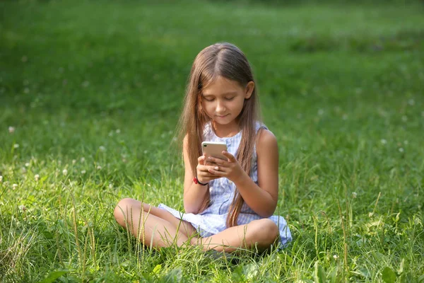 夏の日の公園で携帯電話でかわいい女の子 — ストック写真