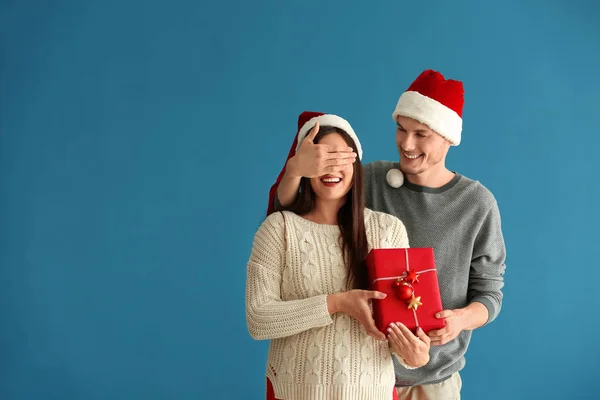 Jovem Mulher Recebendo Presente Natal Seu Marido Fundo Cor — Fotografia de Stock