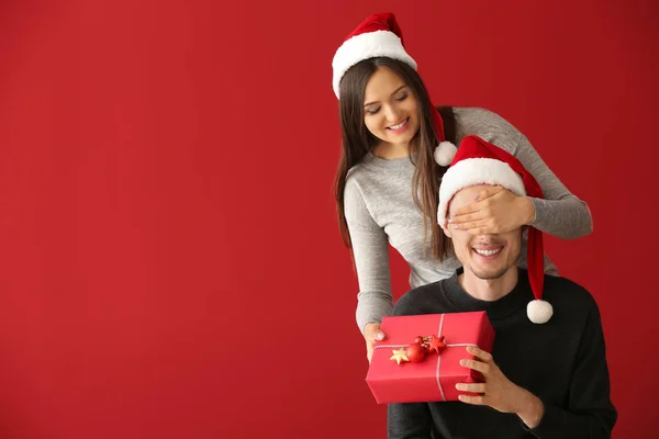 Jovem Recebendo Presente Natal Sua Esposa Fundo Cor — Fotografia de Stock