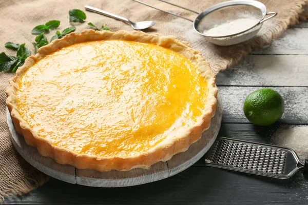 Board with tasty lemon pie on wooden table