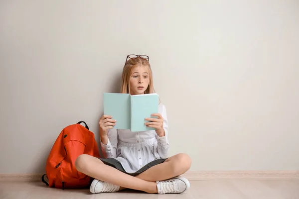 Schattig Schoolmeisje Met Rugzak Zittend Vloer Het Lezen Boek Binnenshuis — Stockfoto