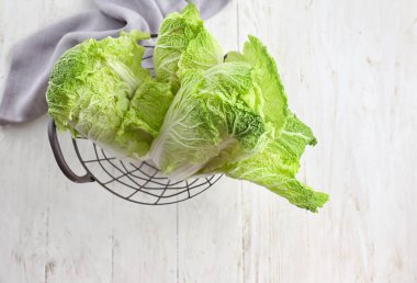 Hafif ahşap masa üzerinde olgunlaşmış taze lahana ile metal sepet