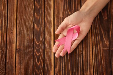 Pembe kurdele ahşap arka plan üzerinde tutan kadın. Meme kanseri kavramı