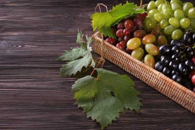 Ahşap masa üzerinde taze Olgun üzüm ile hasır sepet