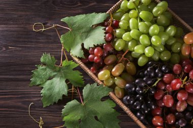 Ahşap masa üzerinde taze Olgun üzüm ile hasır sepet