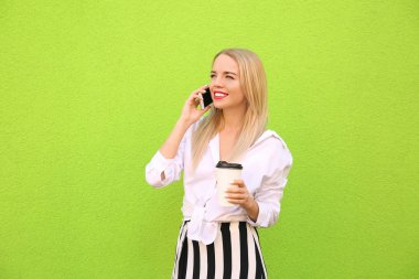 Kahve rengi duvarının yakınında cep telefonu konuşurken olan güzel kadın