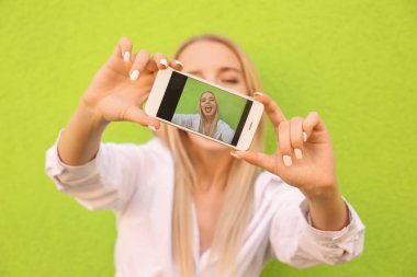 Selfie renk duvarının yakınında alarak güzel genç kadın