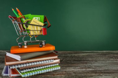 Küçük alışveriş sepeti farklı okul kırtasiye ve renk arka plan karşı masada dizüstü bilgisayarlar ile