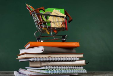 Küçük alışveriş sepeti farklı okul kırtasiye ve renk arka plan karşı masada dizüstü bilgisayarlar ile