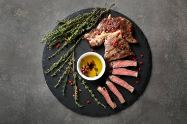 Baharatlar, petrol ve kekik ile ızgara biftek kayrak plaka üzerinde kesmek