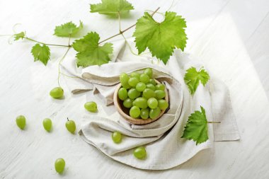 Beyaz ahşap masa üzerinde taze Olgun üzüm ile kase