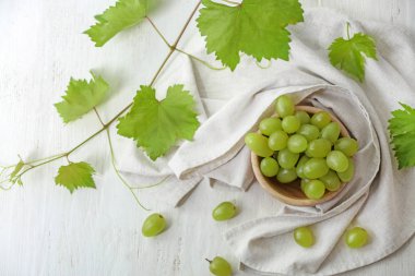 Beyaz ahşap masa üzerinde taze Olgun üzüm ile kase