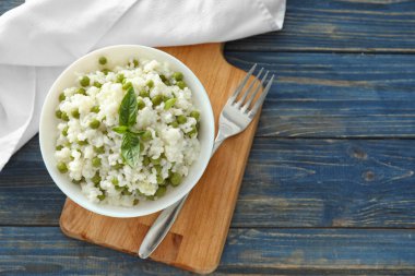 Lezzetli haşlanmış pirinç ve ahşap masa üzerinde bezelye ile kase