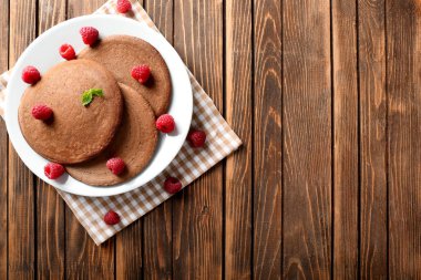 Plaka ile lezzetli çikolatalı krep ve ahududu ahşap tablo