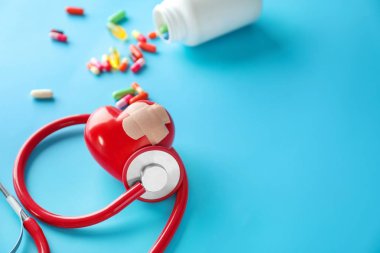 Sağlık stetoskop ve renk arka plan üzerinde sıva ile kırmızı kalp. Kardiyoloji kavramı