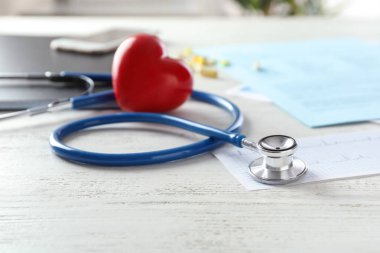 Sağlık stetoskop ve beyaz tahta masada kırmızı kalp. Kardiyoloji kavramı