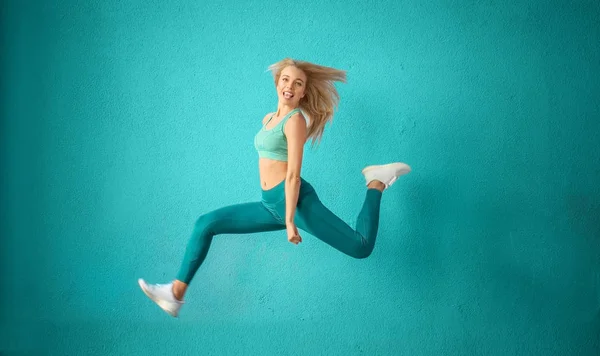 Спортивная Женщина Прыгает Возле Цветной Стены — стоковое фото