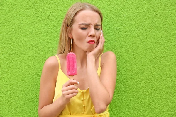 美丽的年轻女子与敏感的牙齿和冷冰淇淋附近的彩色墙 — 图库照片