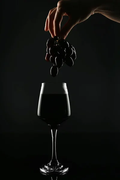 Γυναικείο Χέρι Σταφύλια Πάνω Από Ποτήρι Του Κόκκινου Κρασιού Μαύρο — Φωτογραφία Αρχείου