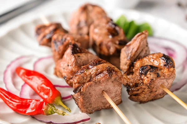 Skewers with delicious shish kebab on plate, closeup