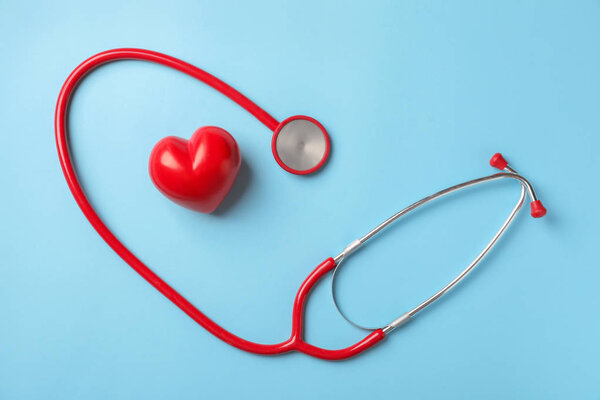 Medical stethoscope and red heart on color background. Cardiology concept