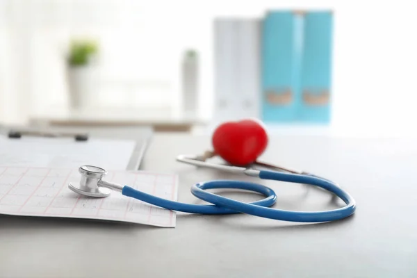 医用听诊器和红色心脏在灰色桌 心脏病学概念 — 图库照片
