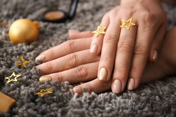 Hands of woman with festive manicure and decor on carpet, closeup