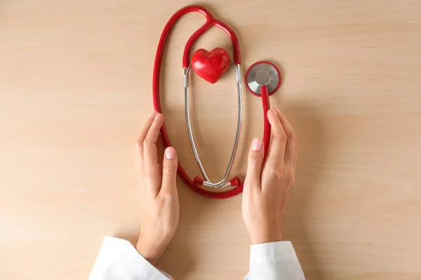 医用听诊器和红色心脏的心脏病专家的手在光背景下 — 图库照片