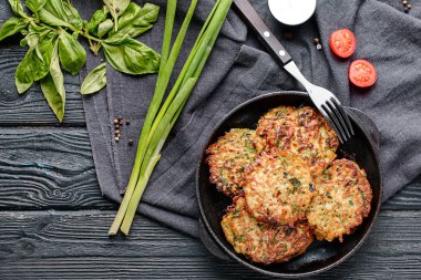 Kızartma tavası lezzetli kabak krep, domates ve ahşap masa üzerinde yeşil soğan ile