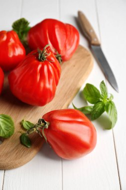 Kurulu lezzetli domates ve beyaz ahşap masa üzerinde taze fesleğen ile