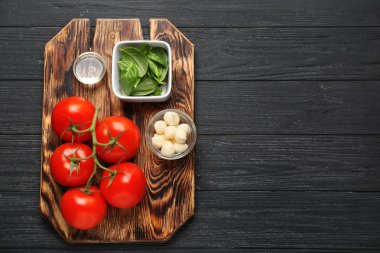 Kurulu lezzetli domates, mozzarella peyniri ve ahşap masa üzerinde taze fesleğen ile