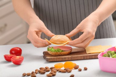 Anne okul öğle yemeği mutfakta masada sandviç yaptırıyor