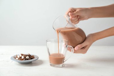 Sürahi gelen lezzetli kakao fincan beyaz tablo içine dökme kadın