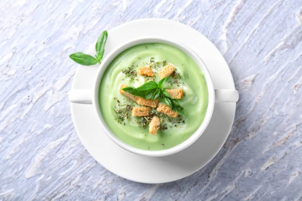 Pot with delicious zucchini soup on light wooden table