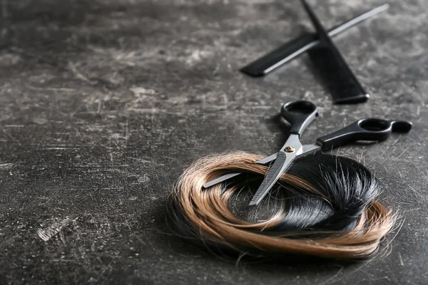 Professional hairdresser's scissors with strands of hair on dark background