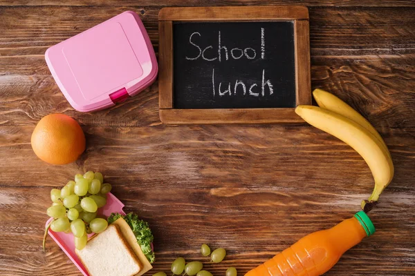 Composition with appetizing food and small chalkboard with words SCHOOL LUNCH on wooden background
