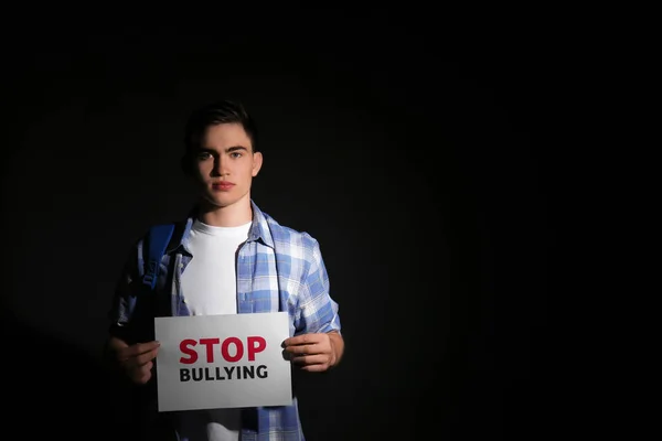 暗い背景にいじめを停止テキストの紙のシートを保持している 代の少年 — ストック写真
