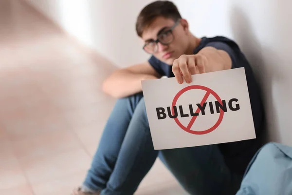 Adolescente Menino Segurando Folha Papel Com Palavra Bullying Enquanto Sentado — Fotografia de Stock